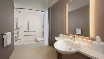 A modern bathroom with a bathtub, a sink, and a large mirror.