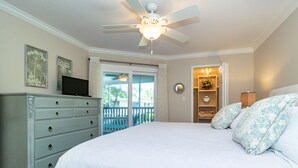Ein Schlafzimmer mit einem großen Bett, einem Schminktisch, einem Deckenventilator und Blick ins Freie.