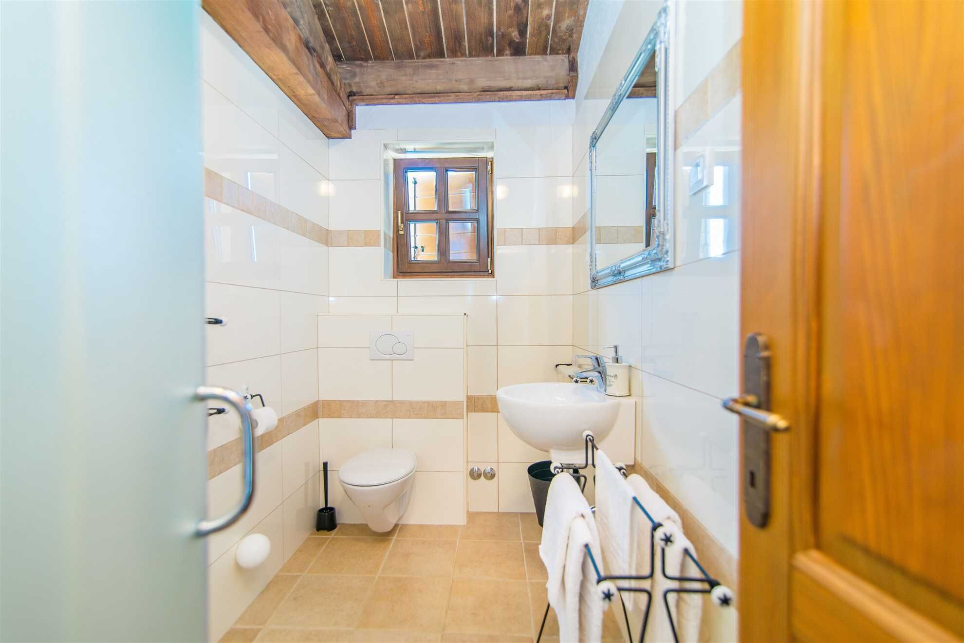 Een badkamer met toilet, wastafel en raam.
