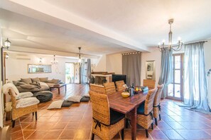 Un amplio salón con una mesa de comedor, sillas de mimbre, un sofá y una chimenea.