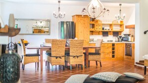 Un comedor con sillas de mimbre, una mesa de madera y una araña.