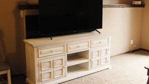 Un moble blanc de televisió amb un televisió de pantalla plana, una prestatgeria a dalt i una presa elèctrica a la paret.