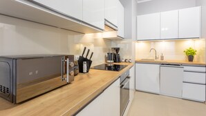 A modern kitchen with white cabinets, stainless steel appliances, and a wooden countertop. - Ferienwohnung am Meer, Urlaub auf der Insel Usedom, Appartement Flora (Swinoujscie)