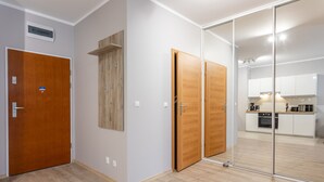 A modern apartment with a wooden door, a mirrored closet, and a kitchen area visible through the mirror. - Ferienwohnung am Meer, Urlaub auf der Insel Usedom, Appartement Flora (Swinoujscie)