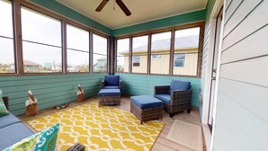 A sunroom with wicker furniture, a patterned rug, and large windows. - Ocean Jewel: 3  BR, 2  BA House in Port Bolivar, Sleeps 10 (Bolivar Peninsula)