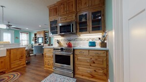 A kitchen with wooden cabinets, a stainless steel oven, and a microwave. - Ocean Jewel: 3  BR, 2  BA House in Port Bolivar, Sleeps 10 (Bolivar Peninsula)