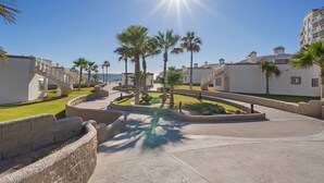 Un resort con un camino curvo, palmeras y una vista despejada del océano.