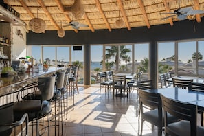 Relax in a spacious indoor area with a high ceiling, featuring a thatched roof design and large windows offering views of the outdoors.