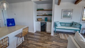 A compact kitchen with white cabinetry, a wooden countertop, and a blue bag on the counter.