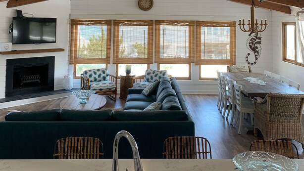 A spacious living area with a high ceiling, a fireplace, a sofa, and a dining table.