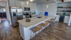 A modern kitchen with white cabinetry, stainless steel appliances, and a central island with bar stools.