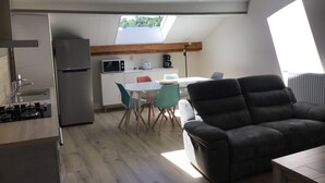 Un espace de vie compact comprenant une kitchenette, un coin repas et un espace détente.