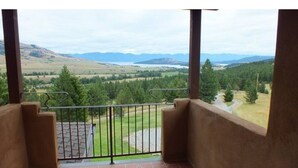 A balcony with a view of a green landscape and distant mountains. - Montana Mountaintop Ranch Estate (Proctor)