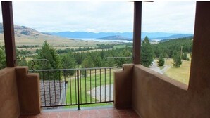 A balcony with a view of a green landscape and distant mountains. - Montana Mountaintop Ranch Estate (Proctor)