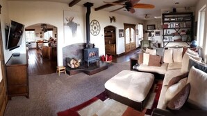 A cozy living room with a fireplace, a sofa, a television, and a bookshelf. - Montana Mountaintop Ranch Estate (Proctor)