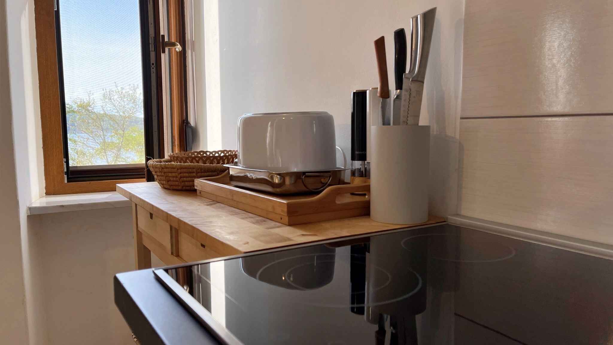 A kitchen with a wooden countertop, a coffee maker, and a set of knives on the wall.