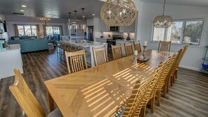 A spacious kitchen with a central island, wooden dining table, and modern pendant lights. - Oceanview, Private Pool, Sleeps 16, Dogs okay, close to beach, PICKLEBALL COURT! (Virginia Beach)