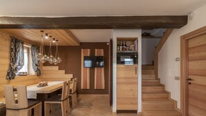 Een moderne keuken met houten kastjes, een ingebouwde oven en een eethoek met een houten tafel en stoelen.