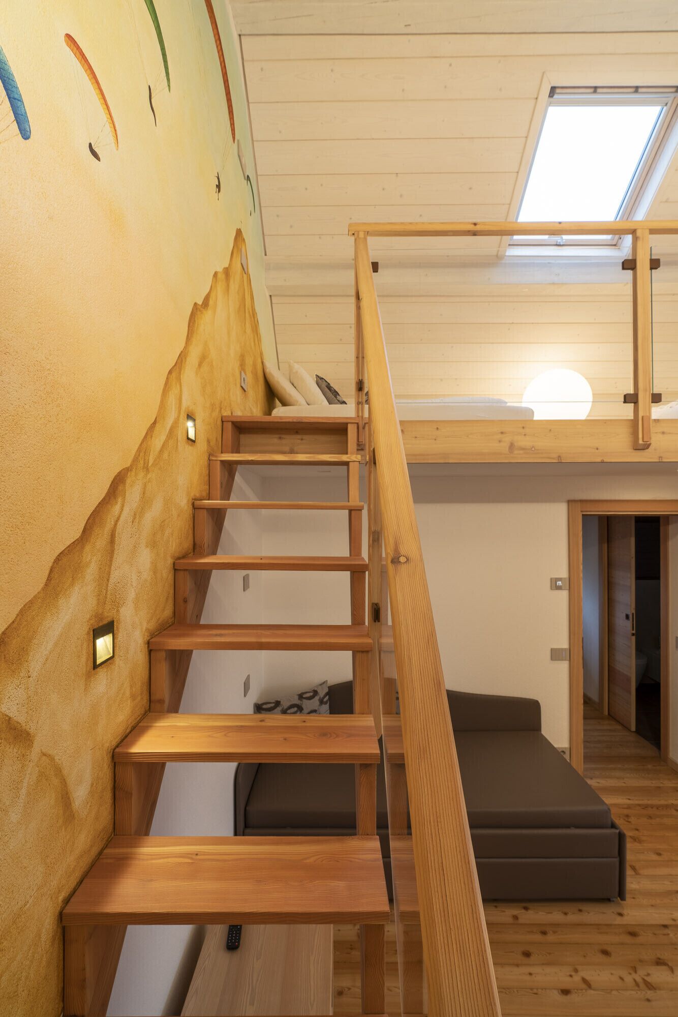 A wooden staircase with a unique wall design, a skylight, and a cozy seating area.