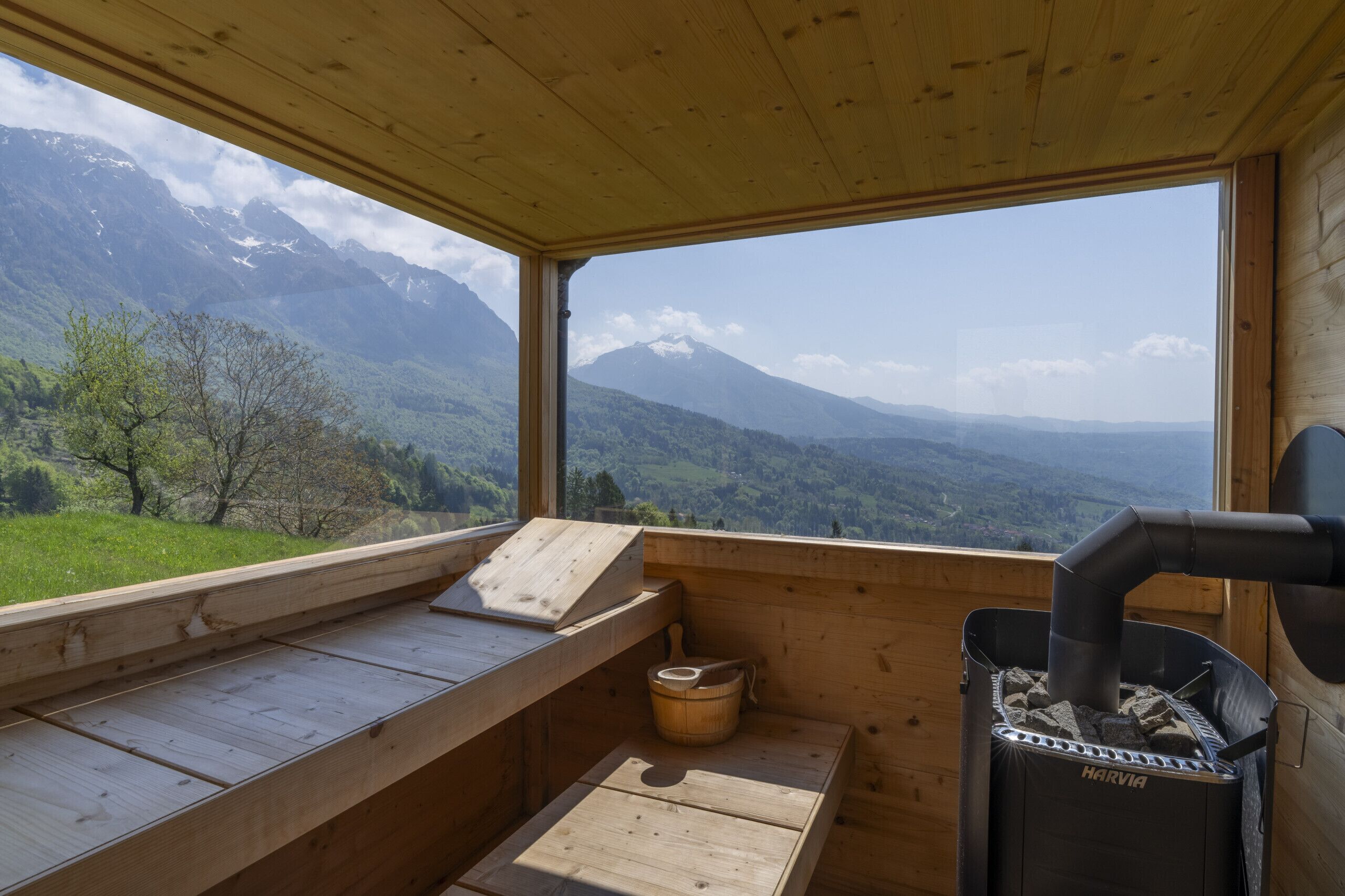 A wooden cabin with a wooden bench and a Harvia wood stove.