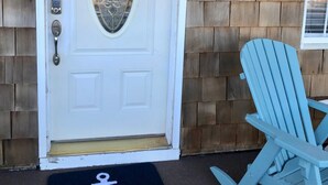 Una puerta blanca con un panel de vidrio decorativo, un teclado de bloqueo y un felpudo con un símbolo de ancla.