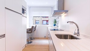 Una cocina moderna con un lavamanos de acero inoxidable, un horno empotrado y un taburete de bar.