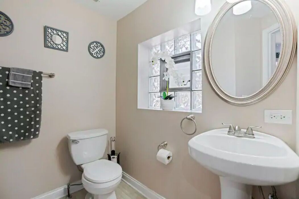 A bathroom with a toilet, sink, and decorative mirror.