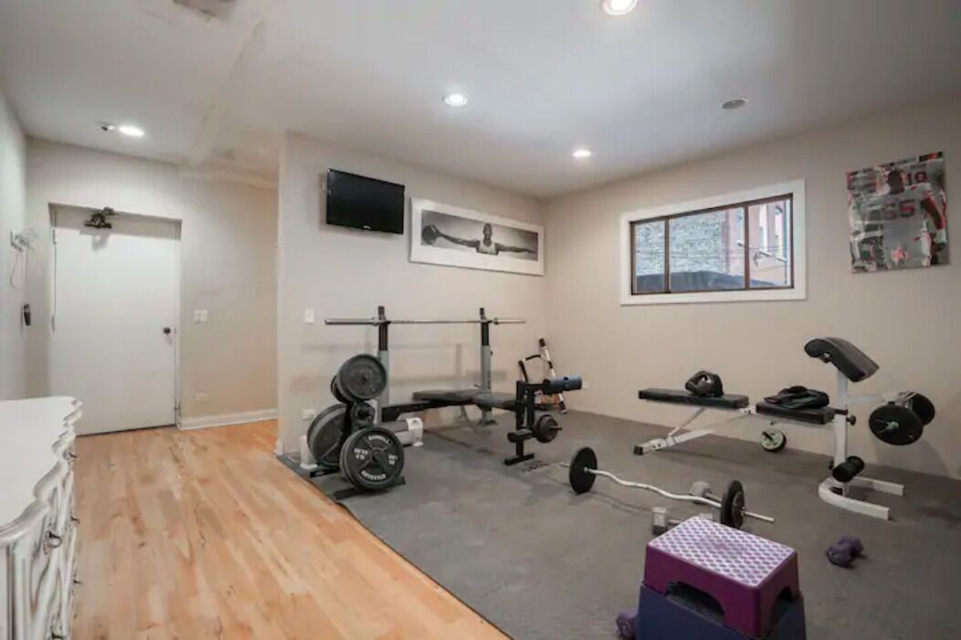 Un gimnasio en casa con banca de pesas, jaula para sentadillas y varios pesos libres.