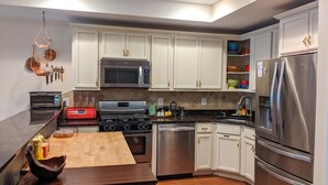 A modern kitchen with white cabinets, stainless steel appliances, and a wooden island.