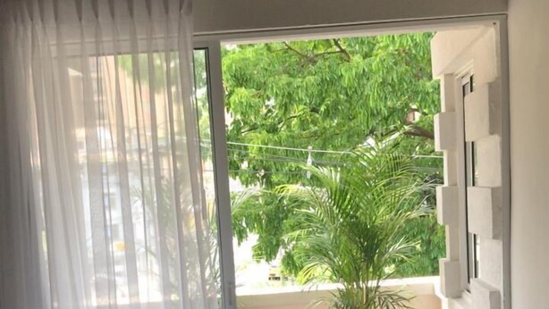 A room with a sliding glass door leading to an outdoor area with a white chair and a potted plant. - Apto muy bien ubicado Home ARIS 402 (Medellín)