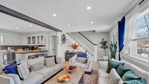 A modern living room with a fireplace, a dining area, and a kitchen.