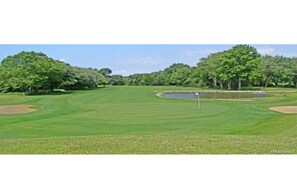 A golf course with a flagstick, water hazards, and trees.