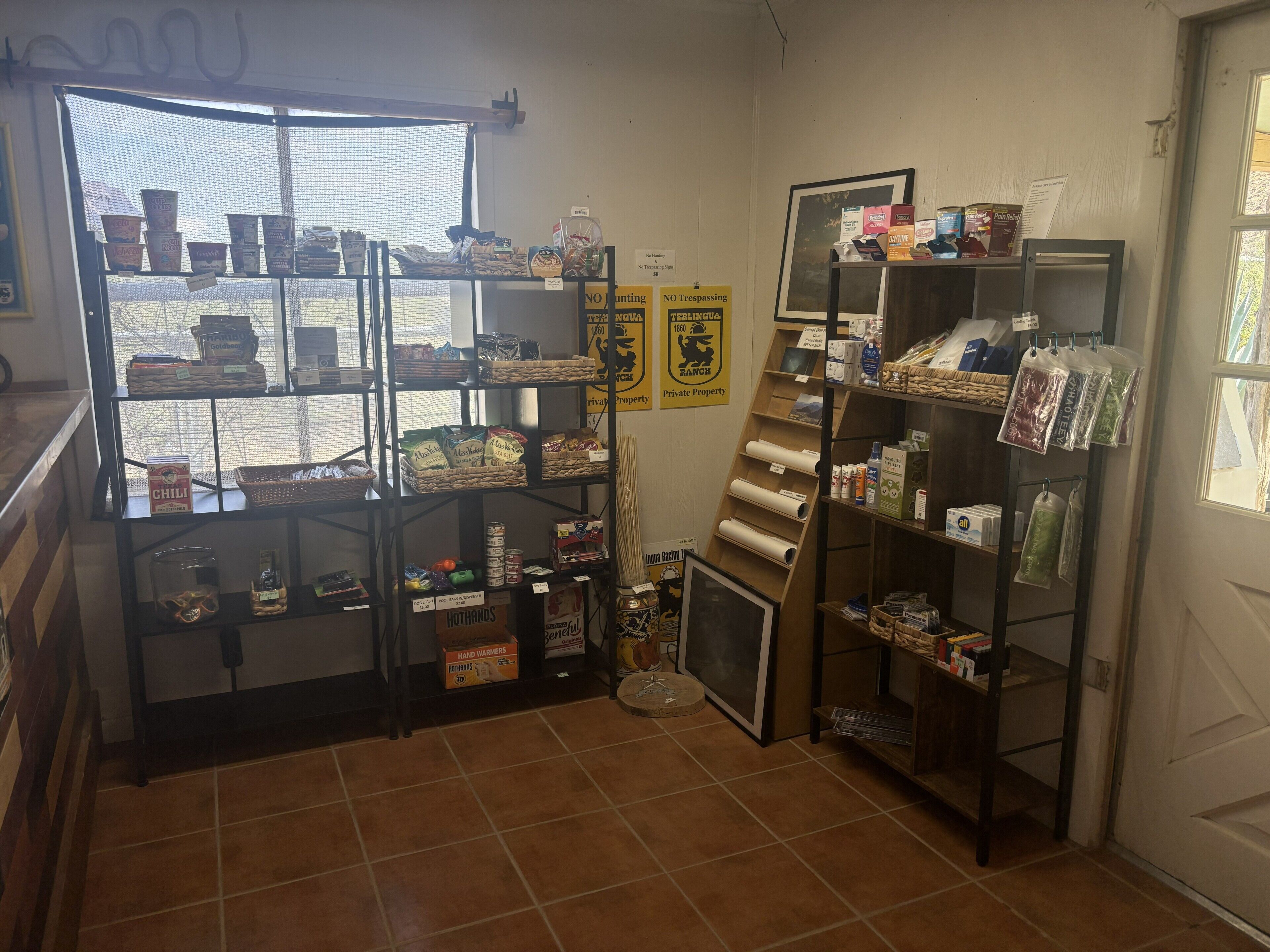 Una tienda con estantes llenos de diversos artículos, una ventana con vistas y una puerta.