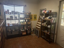 Uma loja com prateleiras cheias de diversos produtos, uma janela com vista e uma porta.