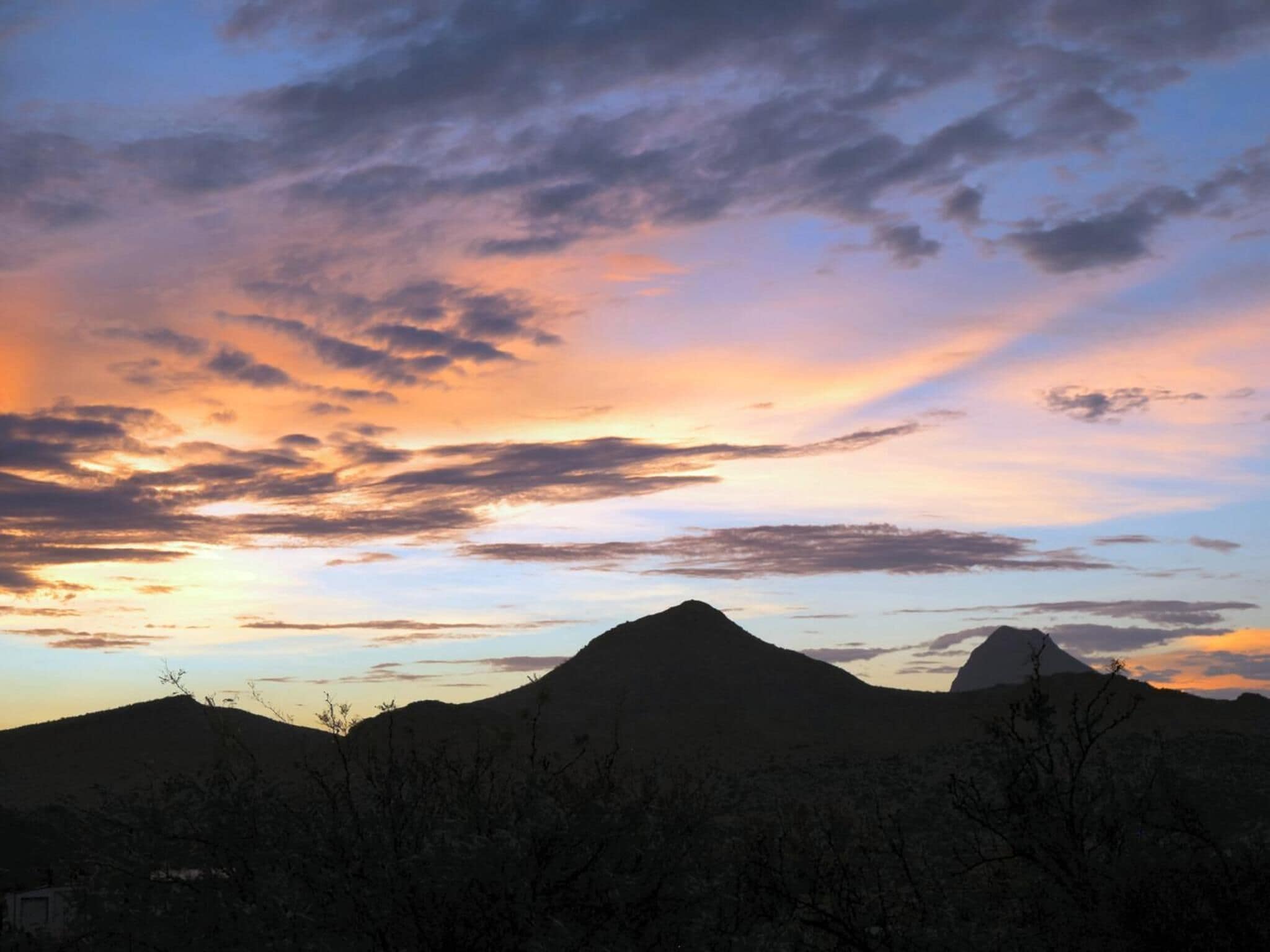 A mountain landscape with a prominent peak during sunset.