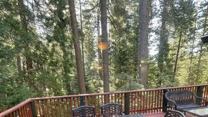 Een overdekt terras buiten met een metalen tafel en stoelen, omgeven door een houten leuning.