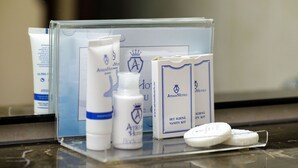 A bathroom counter with toiletries including a bottle, a tube, a box, and two bars of soap. - Atrium Hotel Ateneu City Center (Bucharest)