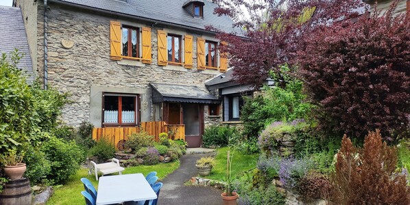 Experience the charm of this rustic stone house, featuring a cozy porch and serene garden with a small pond.