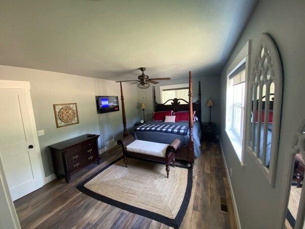 A bedroom with a four-poster bed, a ceiling fan, a television on the wall, and a decorative wall piece. - 4 Seasons Flathead Getaway - Hot Tub & Sauna! (Kalispell)