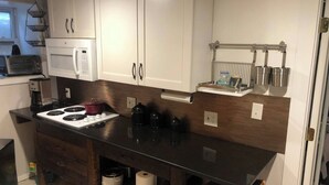 Een keuken met witte kasten, een zwart aanrecht, een magnetron, een fornuis en een koffiezetapparaat.