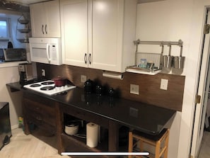 A kitchen with white cabinets, a black countertop, a microwave, a stove, and a coffee maker. - Victorian house, clean comfortable and well located (Boston)