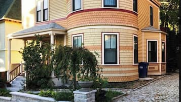 A two-story house with a curved facade, a front porch, and a stone pathway leading to the entrance.