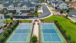 Zona residencial con casas modernas, una cancha de tenis y una calle.