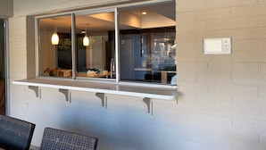 Una habitación con ventana que da a un jardín, una pared de ladrillo blanco y un estante empotrado.