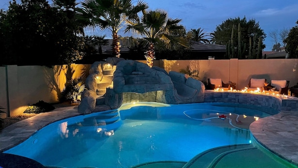Piscina con una formación rocosa y zona de estar.
