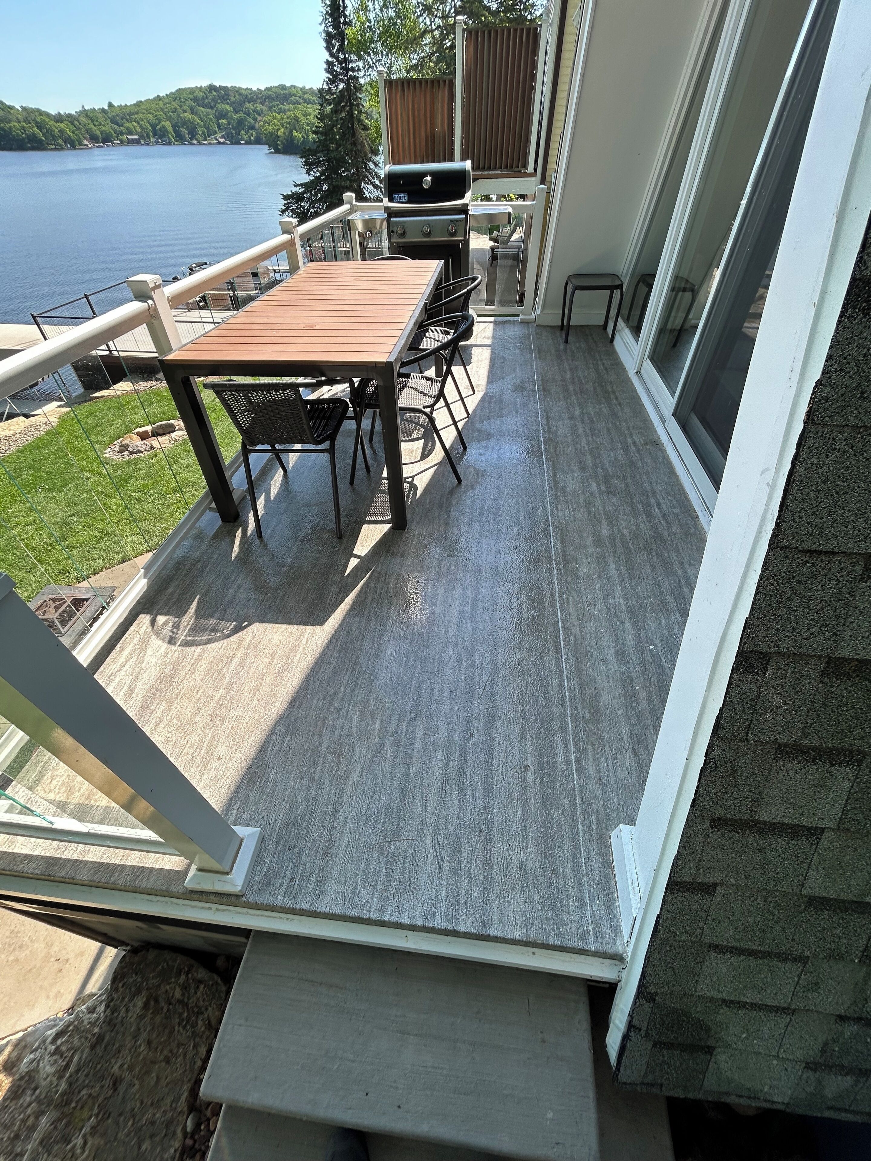 A covered deck with a table and chairs, overlooking a lake.