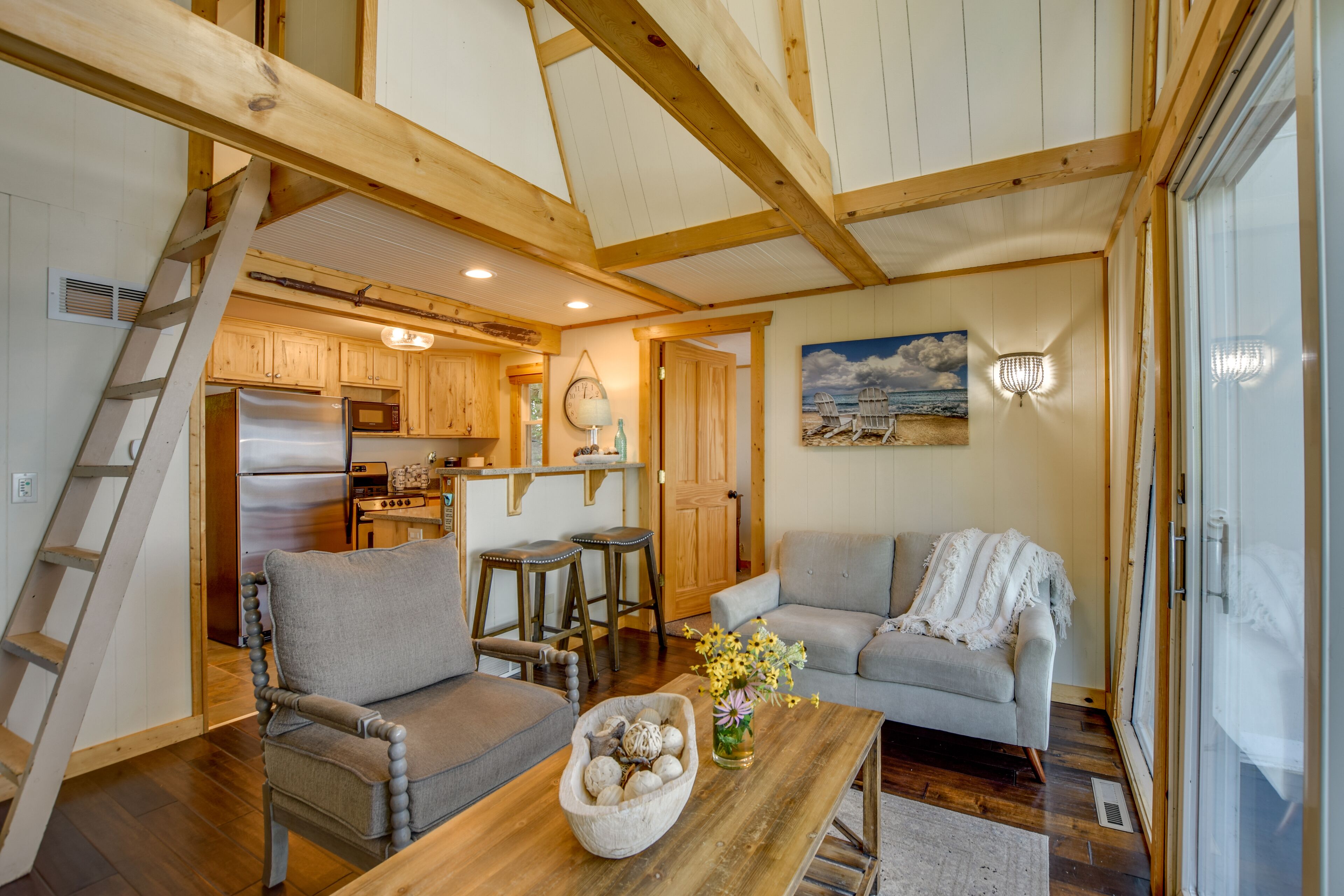 A cozy interior with a wooden staircase, a kitchen area, and a seating area with a sofa and a table.