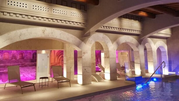 An indoor swimming pool with a stone archway and lounge chairs. - Antica Torre Del Nera (Scheggino)