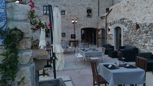 An outdoor dining area with stone walls, tables, and chairs. - Antica Torre Del Nera (Scheggino)