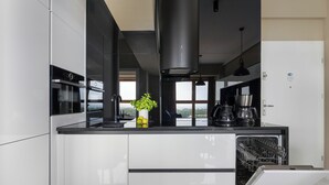 Een moderne keuken met witte kastjes, een inbouwoven, een koffiezetapparaat en een vaatwasser.